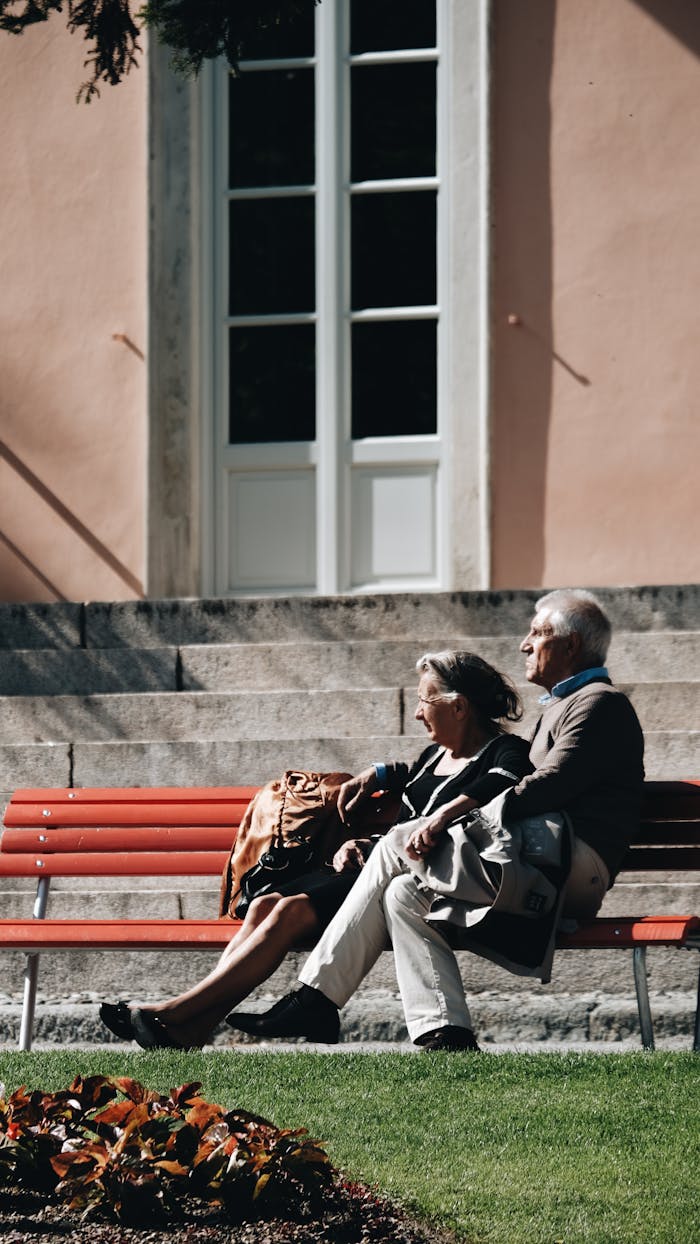 Elderly couple enjoying a serene moment together on a park bench under the sunlight.